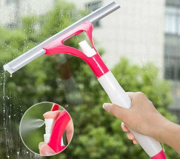 A hand-held spray window squeegee with a pink and white plastic handle, a grey silicone rubber blade, and a small built-in spray pump mechanism showing a close-up of the spray nozzle in action.